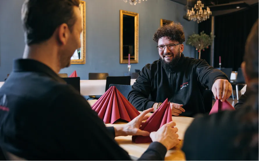 Zwei Männer sitzen an einem festlich gedeckten Restauranttisch mit roten Stoffservietten