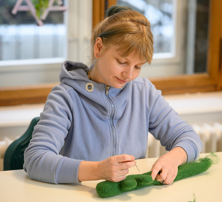 Kind spielt mit grünen Holzbausteinen am Tisch