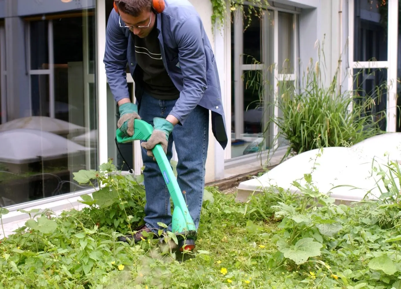 Mitarbeiter*in des Hausdienstes bei der Gartenpflege im Aussenbereich von Weizenkorn