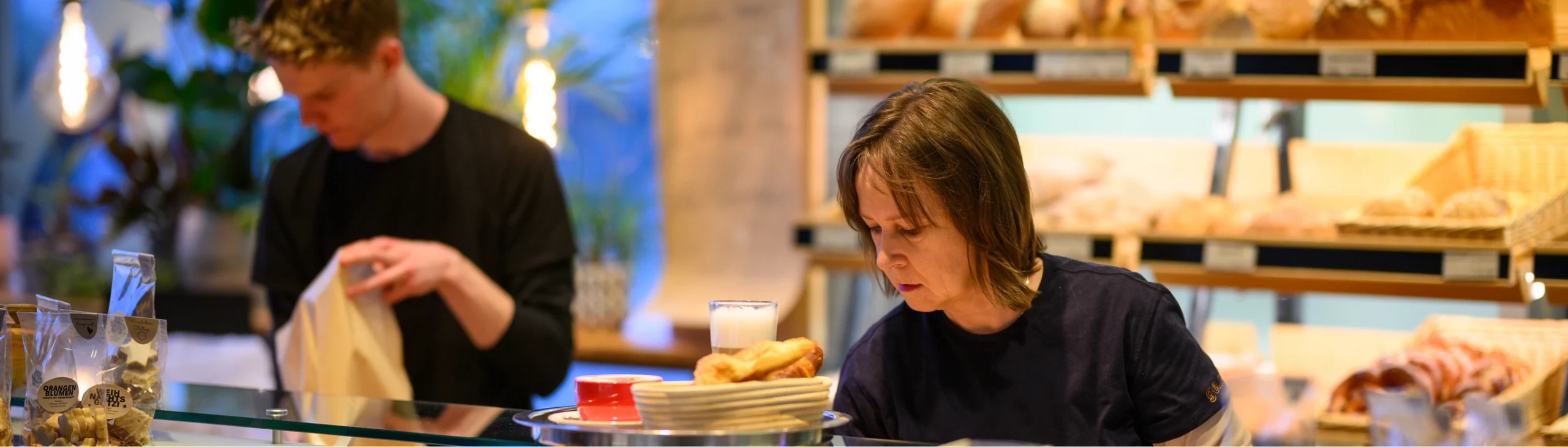 Frau isst ein Sandwich an einem Cafétisch