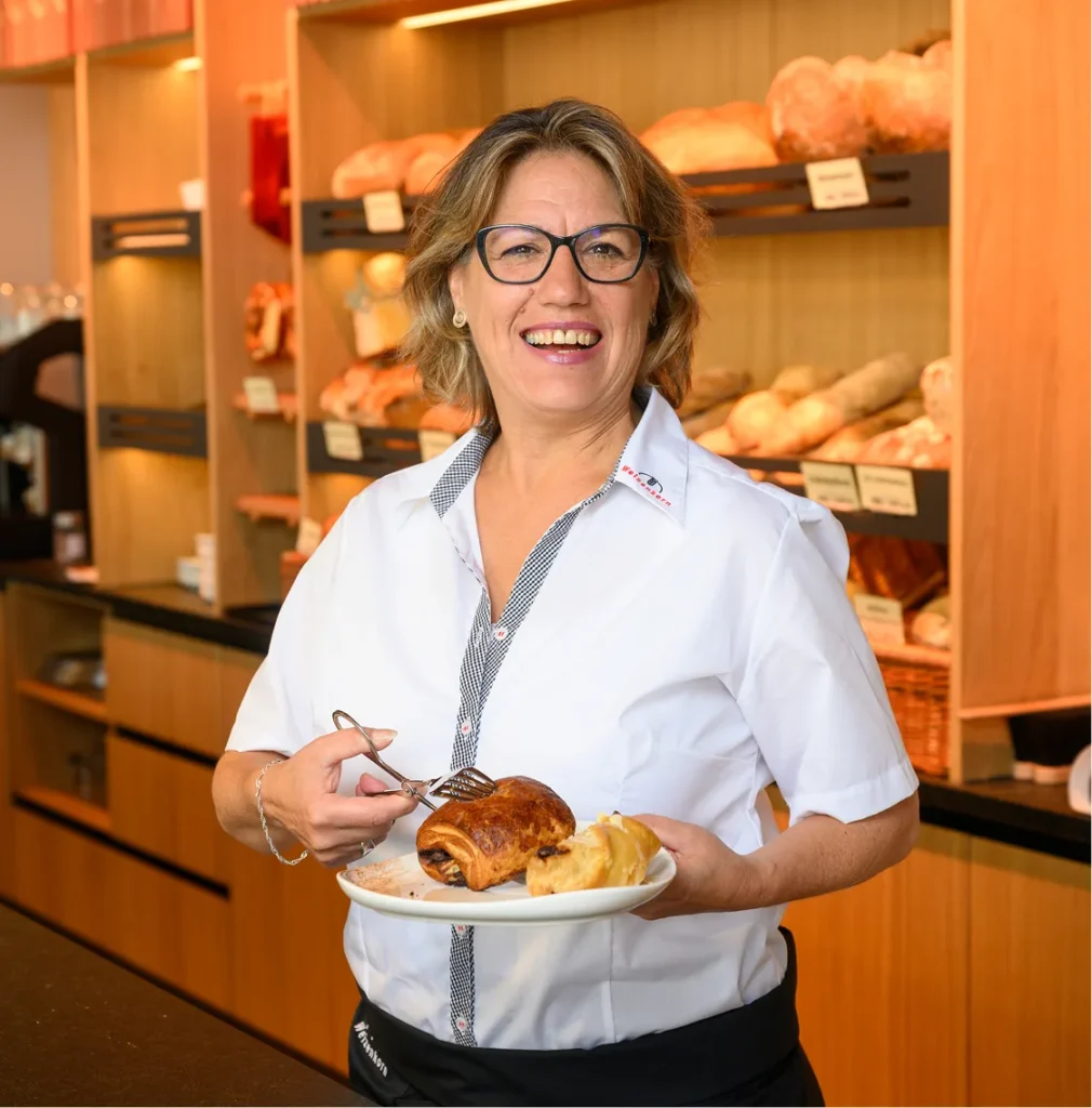 Mitarbeiterin in der Bäckerei-Filiale von Weizenkorn mit frischem Brot