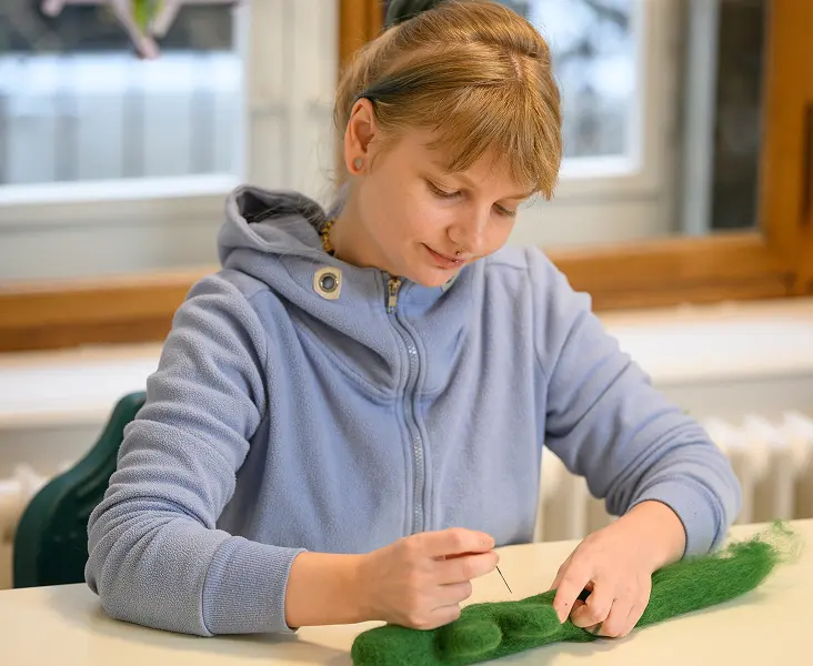 Mitarbeiter arbeitet an einem Tisch mit grünem Bastelmaterial