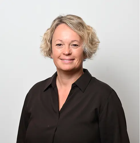 Porträt von Marie Mahé, lächelnd vor neutralem Hintergrund
